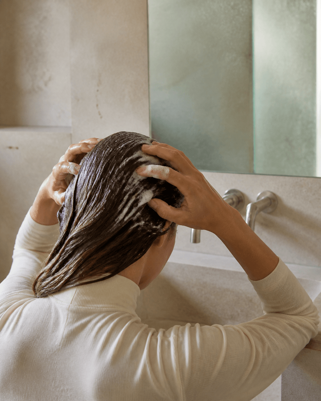 Mujer masajeando su cuero cabelludo durante el lavado